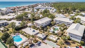 Eine Luftaufnahme eines Küstenresorts mit mehreren Gebäuden, einem Schwimmbad und einem Strand im Hintergrund.