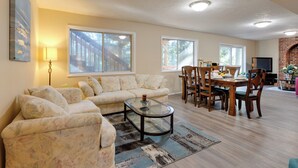 A living room with a sofa, a glass coffee table, and a dining area with a table and chairs. - Oregon Jade Lodging- Spacious 2 Bedrooms, Ev Charger, Quite By Stream (West Linn)
