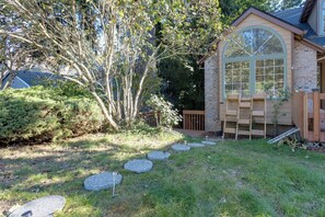 A house with a stone facade, a large arched window, and a wooden deck. - Oregon Jade Lodging- Spacious 2 Bedrooms, Ev Charger, Quite By Stream (West Linn)