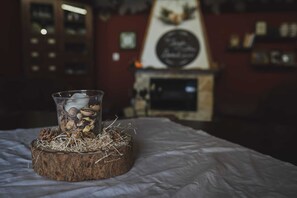 A glass filled with nuts and dried plants on a wooden coaster on a bed. - " il Rifugio di Aitna " (Ragalna)