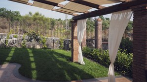 A covered patio area with a brick wall, a stone wall, and a metal fence. - " il Rifugio di Aitna " (Ragalna)