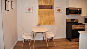 Cocina compacta con comedor, que incluye estufa, microondas y una pequeña mesa con sillas.
