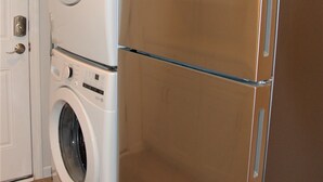 Una cocina compacta con refrigerador de acero inoxidable y lavadora y secadora integradas.