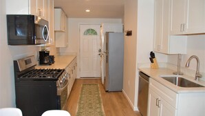 Cocina compacta con estufa, microondas, refrigerador y lavaplatos.