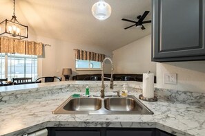 Enjoy meals in this kitchen with a sink, pendant light, and window.