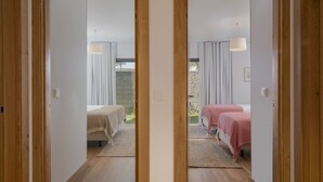 A mirrored view of a room with two beds, a window, and a view of greenery outside. - Casas do Miradouro 6 by Heart of Funchal (Funchal)