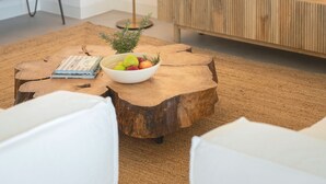 A modern living room with a wooden coffee table, a bowl of fruit, a floor lamp, a flat-screen TV, and a colorful bench. - Casas do Miradouro 6 by Heart of Funchal (Funchal)