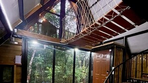 A spacious room with a large sliding glass door leading to a forested area, a wooden staircase, and a view of the outdoors. - Aqeel Cabin in Nature and River (Churuquita Grande)