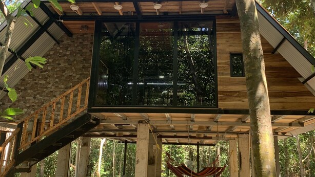 A treehouse with a wooden deck, large windows, and a hammock. - Aqeel Cabin in Nature and River (Churuquita Grande)
