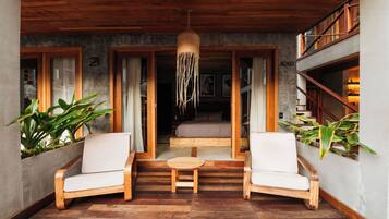 A cozy seating area with two chairs and a small table, wooden flooring, and a hanging light fixture.