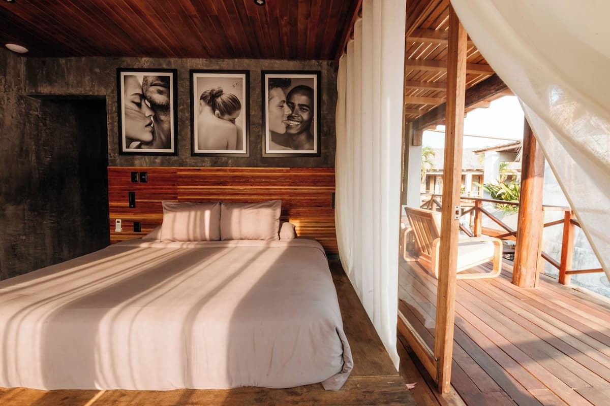 Een slaapkamer met een houten hoofdeinde, een groot bed en drie ingelijste foto’s aan de muur.