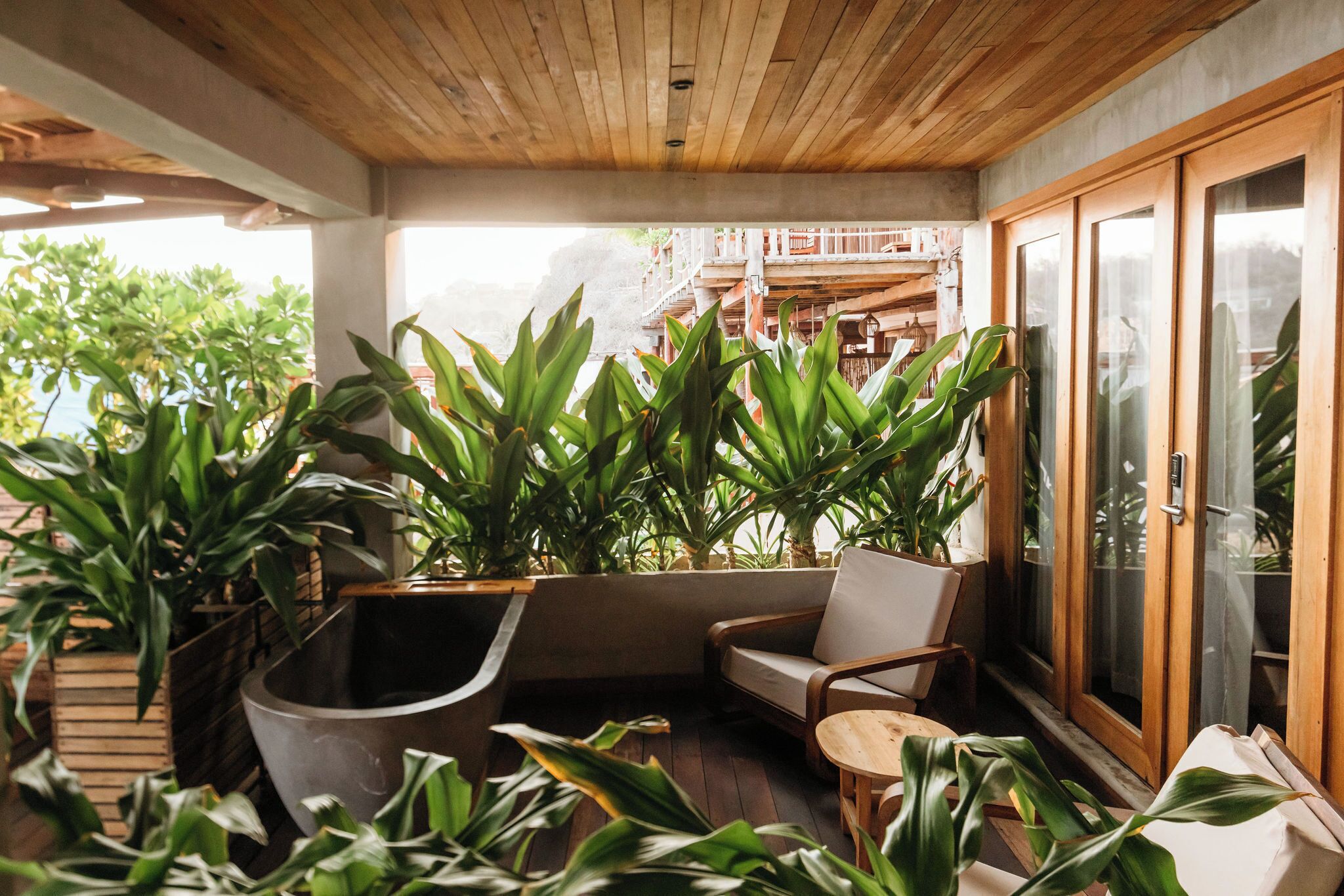 Un rincón exterior acogedor con mobiliario de madera y grandes macetas.