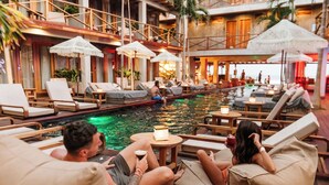 Un espace aménagé au bord de la piscine, avec des chaises longues, des parasols et une piscine.