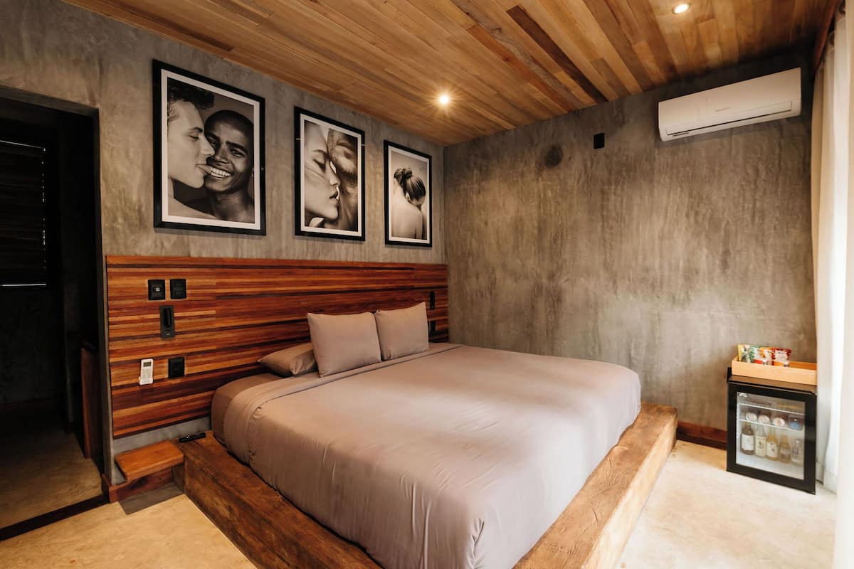 Een moderne slaapkamer met een houten hoofdeinde, een groot bed en een minibar.
