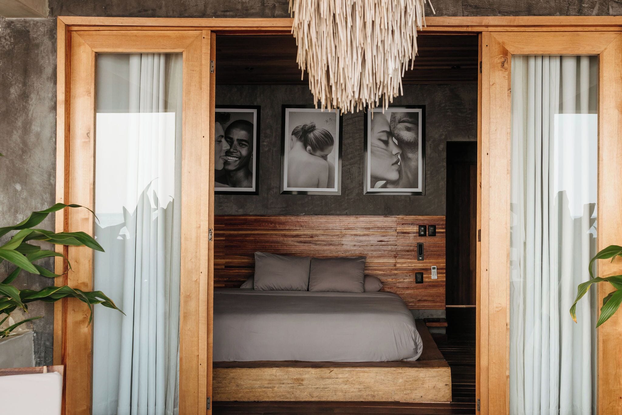 Ein Schlafzimmer mit einem Holzkopfteil, einem Bett mit grauer Bettwäsche und gerahmten Bildern an der Wand.