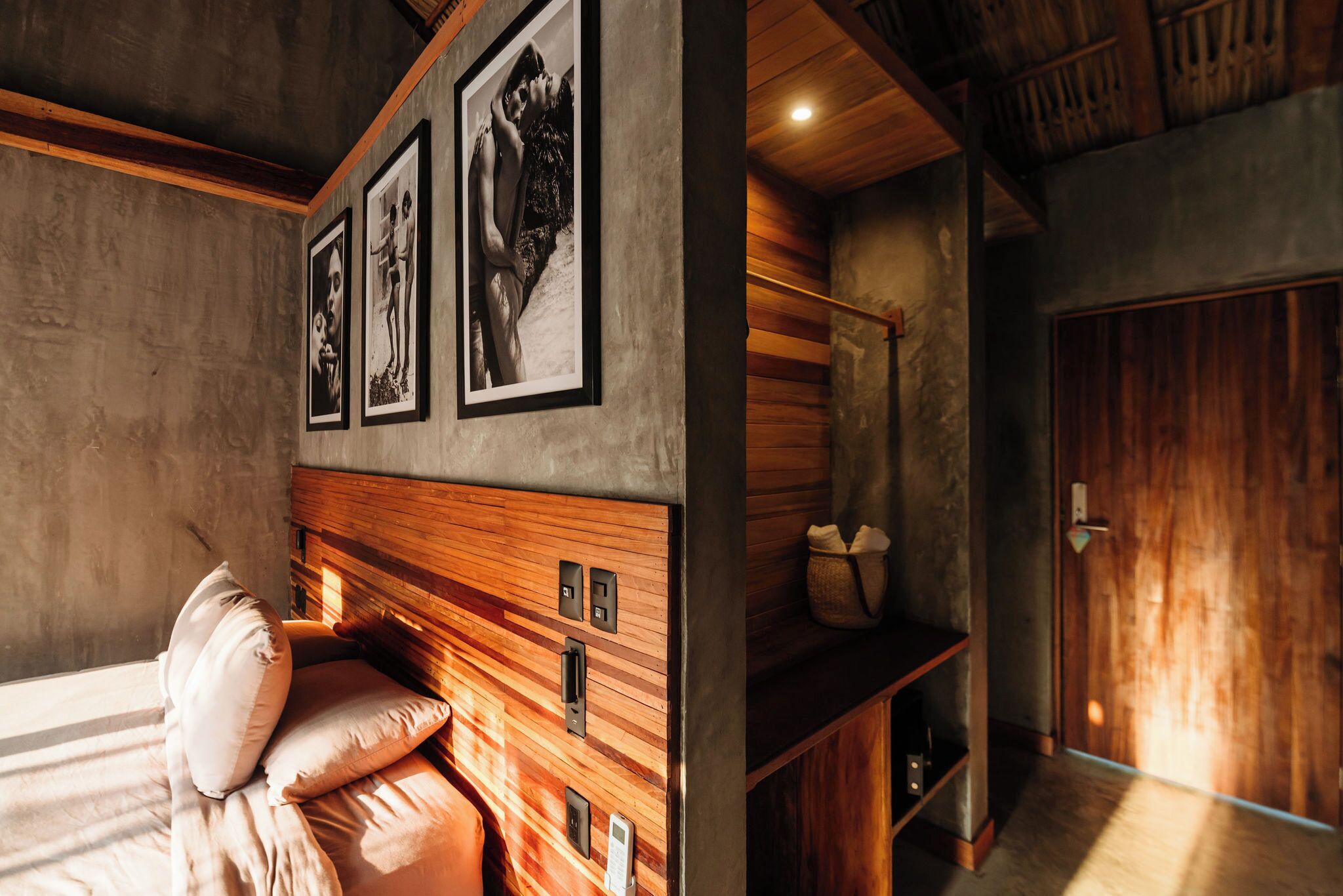 Un dormitorio con cabecera de madera, cama con almohadas, mesita de noche y estante montado en la pared.
