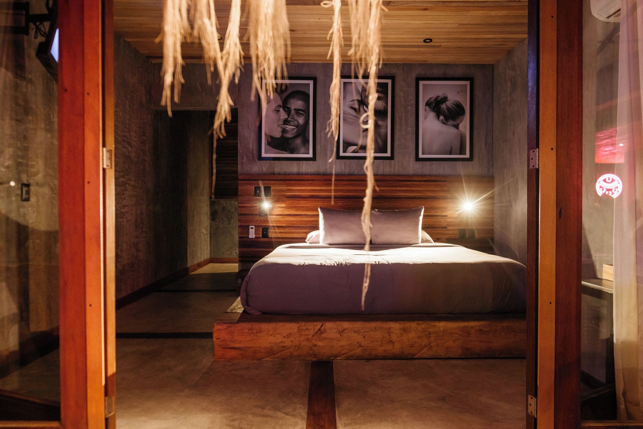 Camera da letto moderna con una struttura letto in legno, una testata con illuminazione integrata e fotografie incorniciate alle pareti.