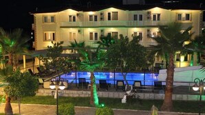 A hotel with a swimming pool, outdoor seating, and palm trees. - Hotel Gold Stone (Kemer)