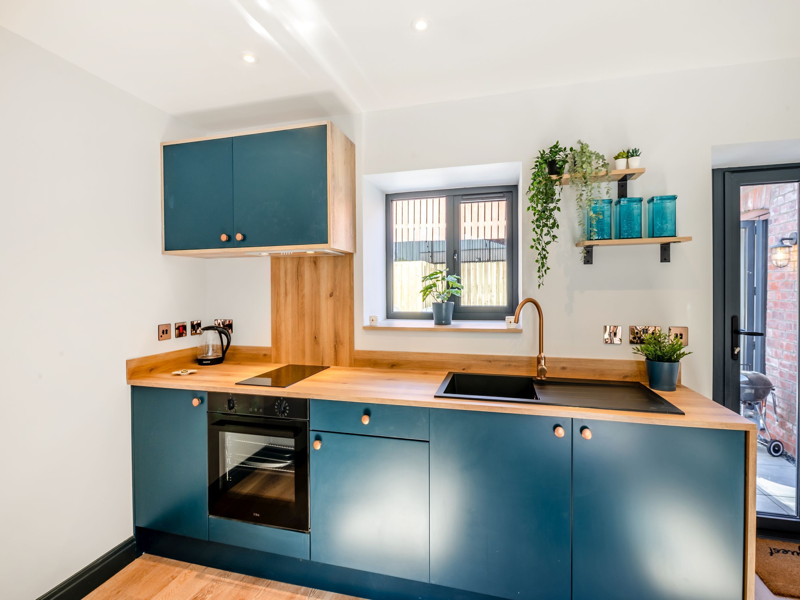 A modern kitchen with a built-in oven, a sink, and a window with a view of the outside.