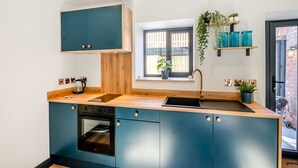 A modern kitchen with a built-in oven, a sink, and a window with a view of the outside. - We just love this romantic barn conversion. (Skirlaugh)