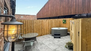 A patio with a hot tub, a table with chairs, and a lantern. - We just love this romantic barn conversion. (Skirlaugh)