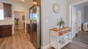 Eine moderne Küche mit Holzschränken, einem Edelstahlkühlschrank und einem Holztischchen mit einer Pflanze.
