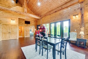 A wooden interior with a dining area, chairs, a table, and a television. - Gatlinburg Vacation Rental w/ Private Hot Tub! (Gatlinburg)