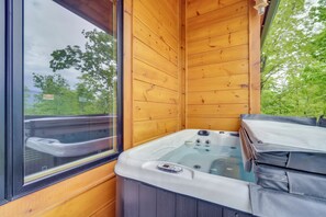 Une cabane en bois avec un jacuzzi, une fenêtre et une vue sur les arbres.