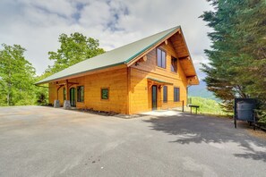 Une cabane en bois avec un toit en pente, une véranda à l’avant et une allée menant à l’entrée.
