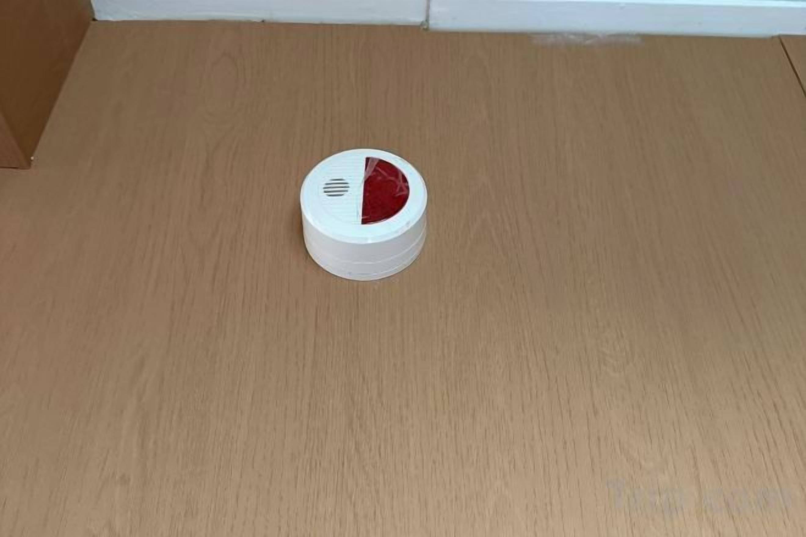 A white object with a red section on a wooden floor.