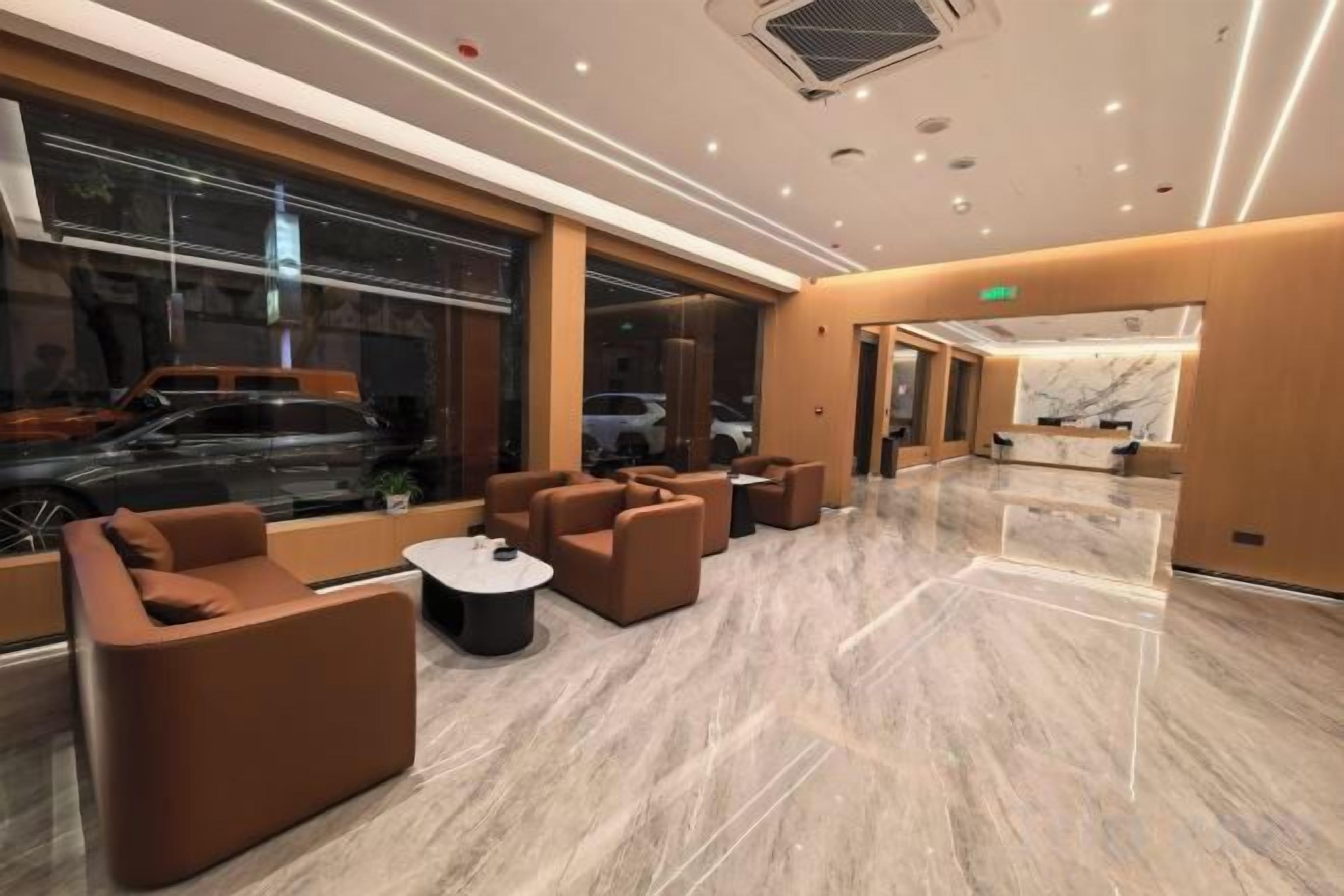 A modern hotel lobby with seating areas, a reception desk, and large windows.