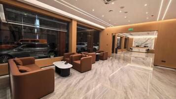 A modern hotel lobby with seating areas, a reception desk, and large windows.
