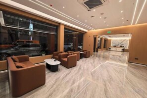 A modern hotel lobby with seating areas, a reception desk, and large windows. - Shitai New Century Hotel (Shitai)