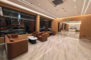 Un moderno vestíbulo de hotel con áreas de estar, una recepción y ventanas amplias.