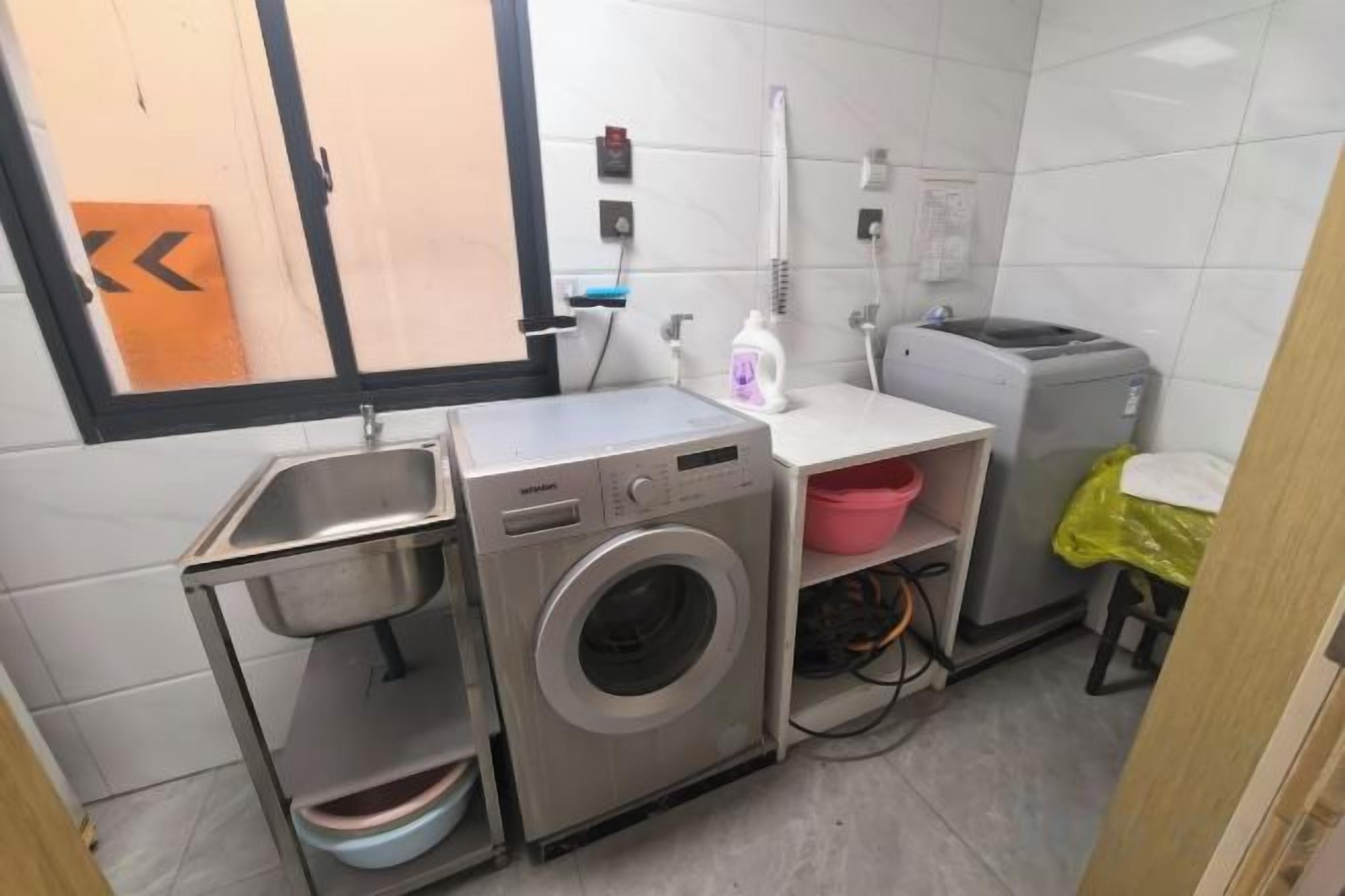A compact kitchen with a washing machine, a sink, and a small countertop.