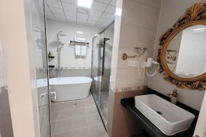 A modern bathroom with a glass-enclosed shower, a freestanding bathtub, and a vanity with a sink. - Shitai New Century Hotel (Shitai)