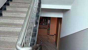 A staircase with metal handrails leading to a room with a wooden floor and a white wall.