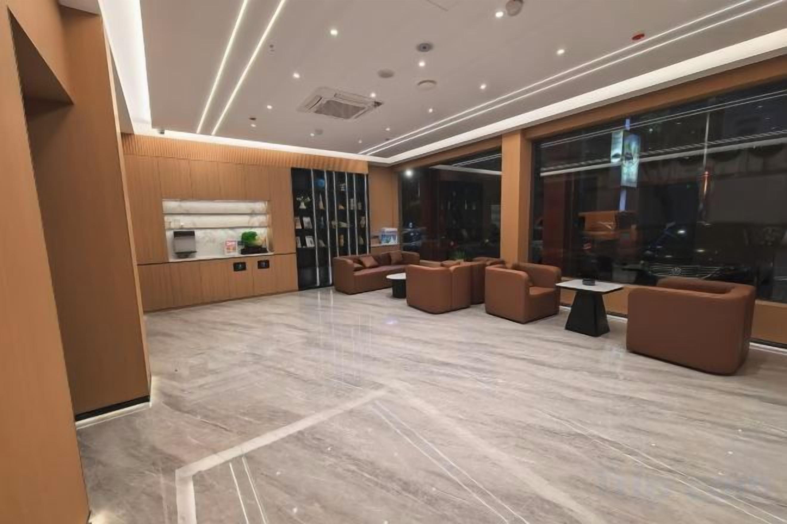 A modern lobby with a reception desk, seating area, and large windows.