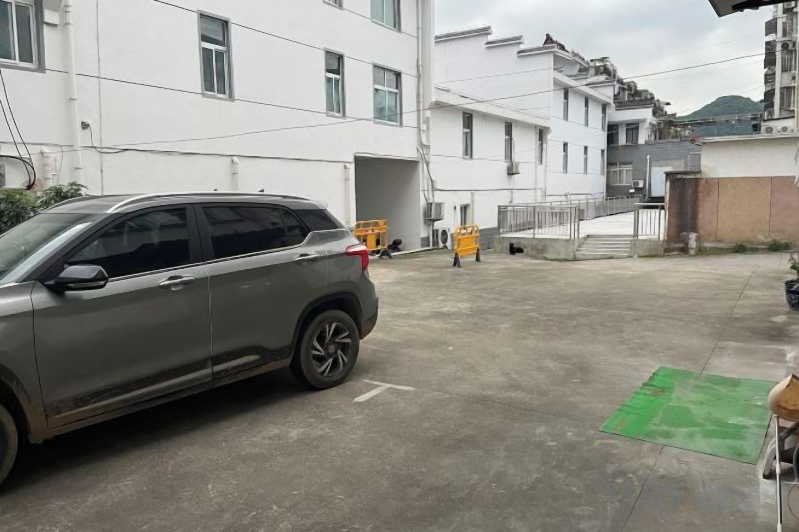 A parking area with a car and a building in the background.