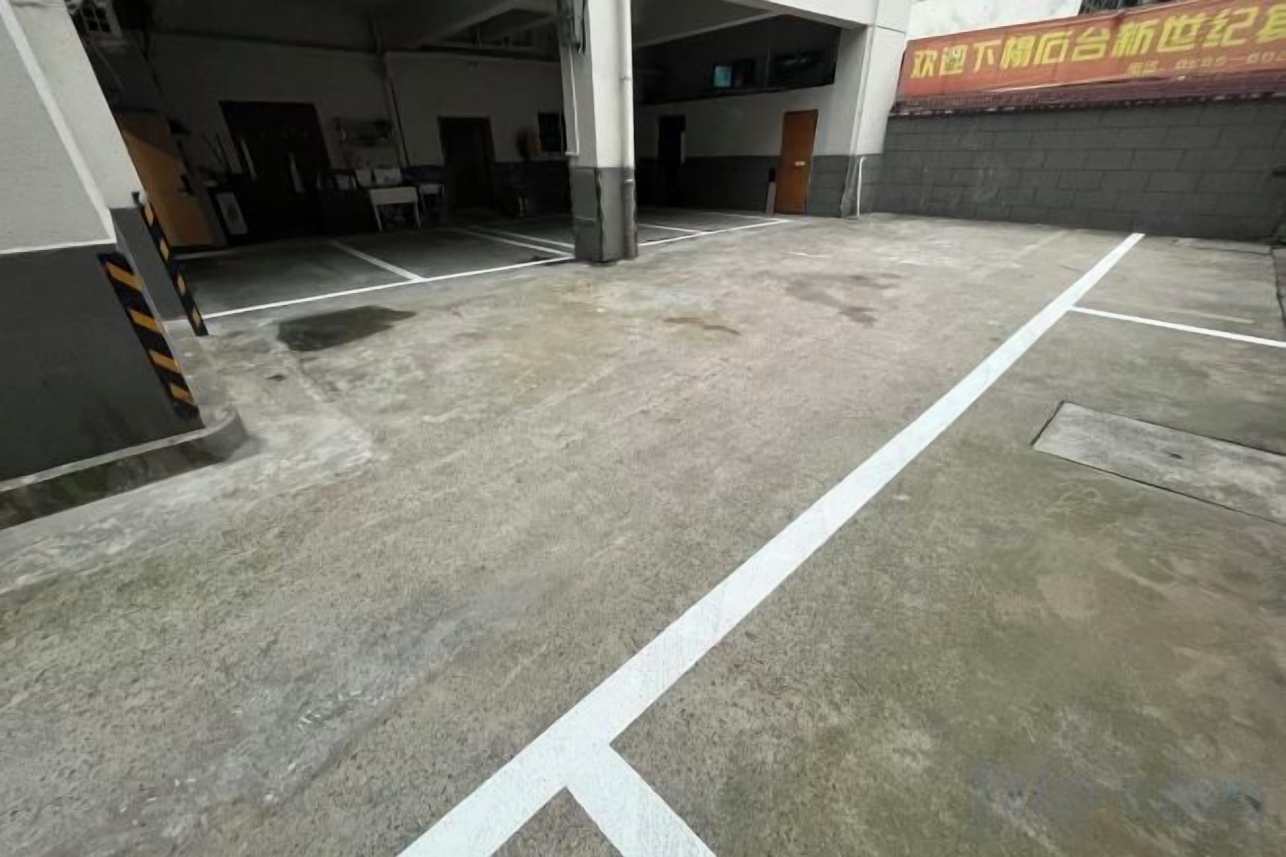 A parking area with concrete surfaces and white lines marking parking spaces.