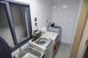 Una cocina pequeña y limpia con un lavamanos, una lavadora y un bote de basura.