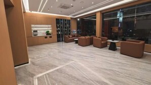 Un hall d’entrée moderne avec un comptoir d’accueil, un espace salon et de grandes fenêtres.