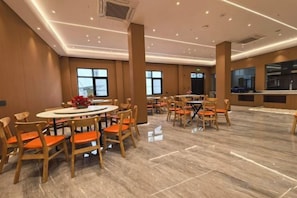 A hotel dining area with round tables and chairs, large windows, and a modern interior design. - Shitai New Century Hotel (Shitai)