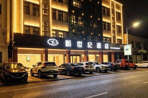 A hotel with a signboard, multiple parked cars, and a well-lit facade at night. - Shitai New Century Hotel (Shitai)