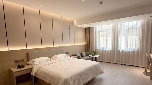 Une chambre d’hôtel moderne avec un grand lit, une table de chevet et une petite table ronde agrémentée d’une plante.