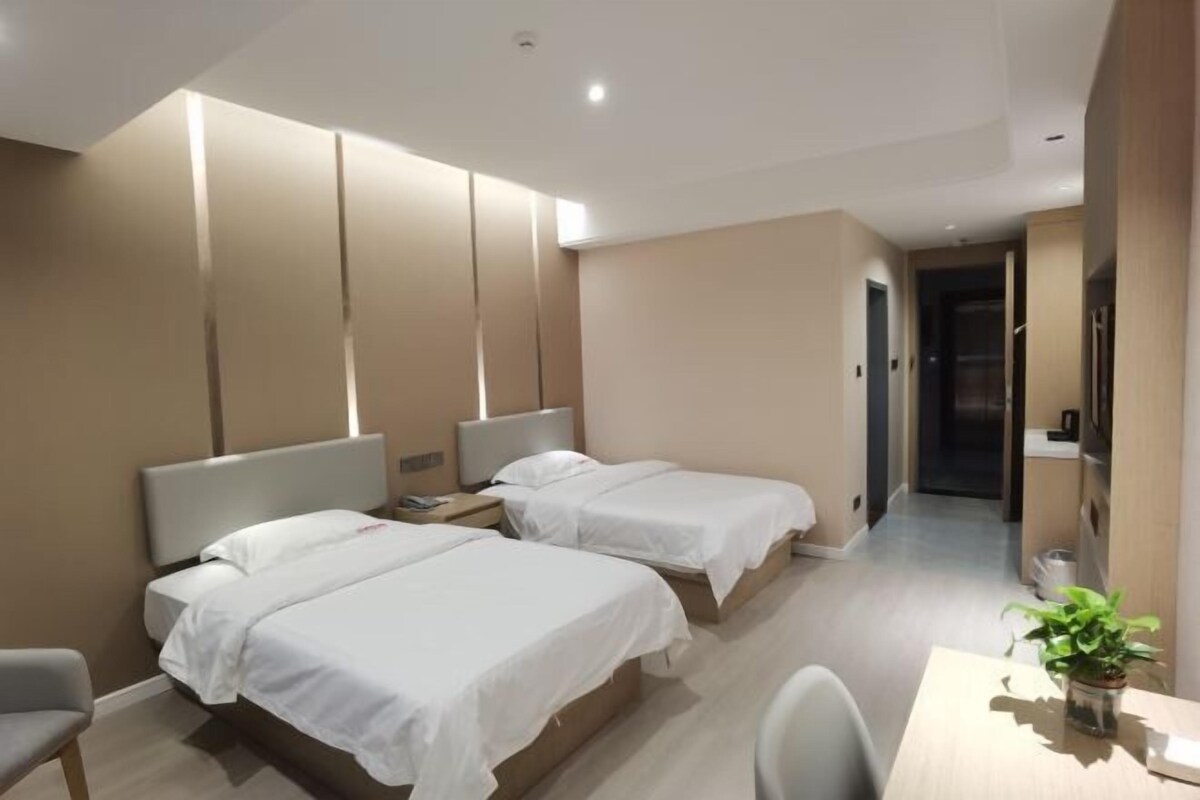 A modern hotel room with two beds, a desk, and a chair.