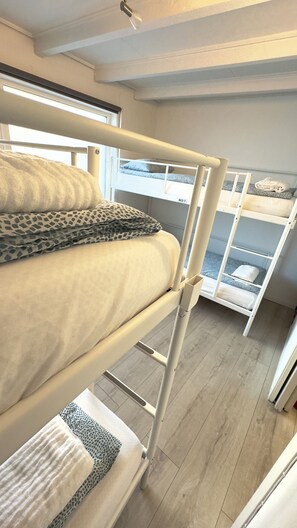 Habitación con literas, una escalera, una ventana y ropa de cama estampada.