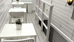 A covered patio area with white furniture, including a table and chairs, and a potted plant. - Central Economic Stavanger (Stavanger)