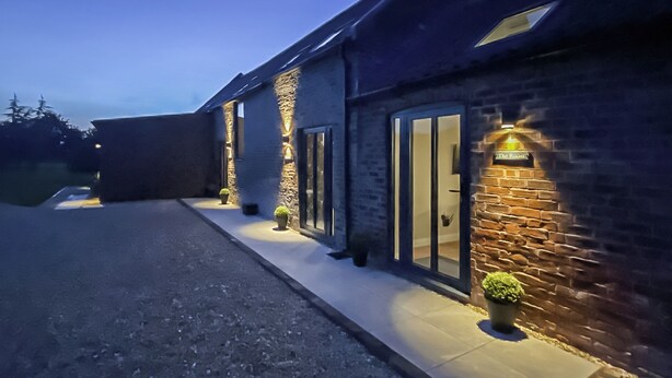 Un edificio con fachada de piedra, puertas de cristal grandes e iluminación exterior.