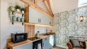 Una cocina funcional con vigas de madera, electrodomésticos integrados y un papel pintado floral.